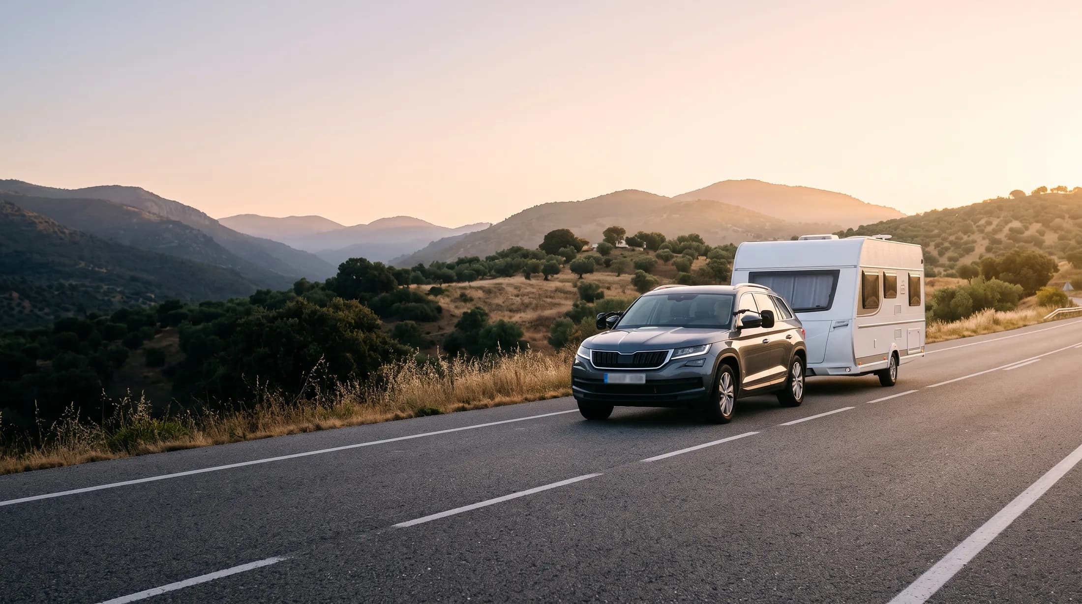 Coche remolcando una caravana por una carretera entre montañas